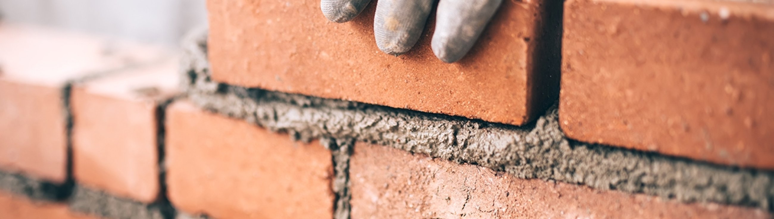 Close up of industrial bricklayer installing bricks on construction site